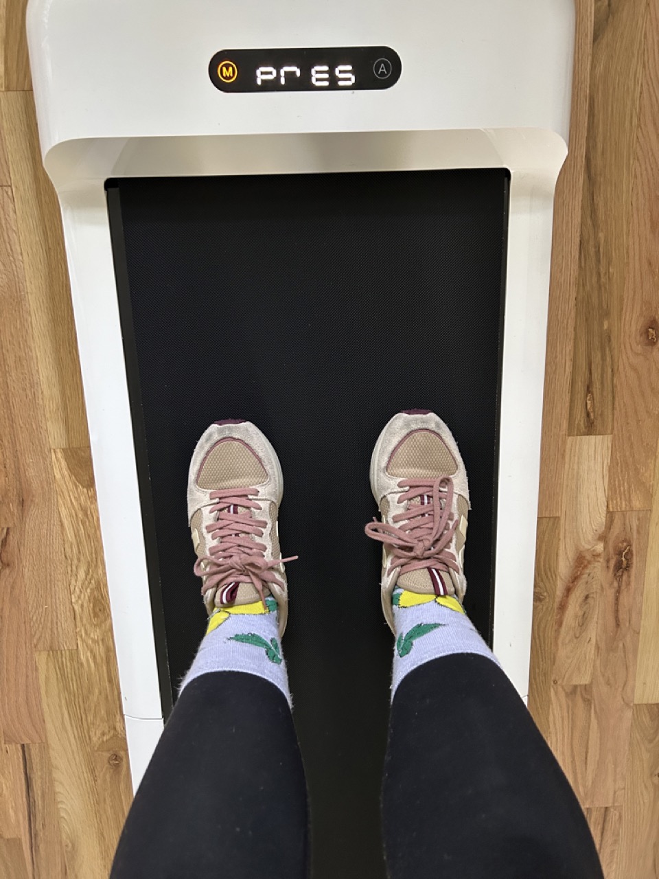 A shot from above of a person's feet on the WalkingPad wearing running shoes.