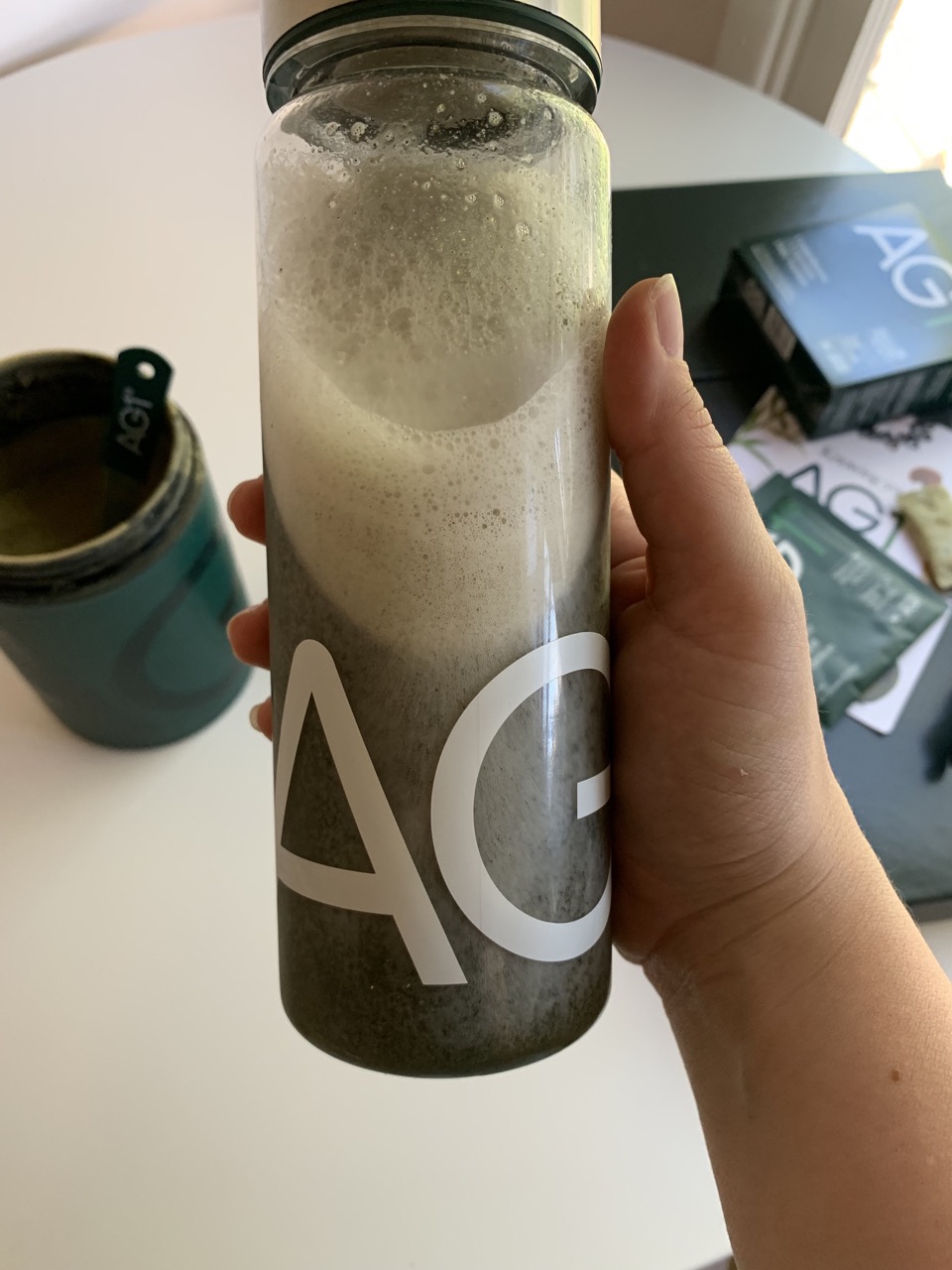 An image of a hand holding the drink mixed in the glass bottle. 