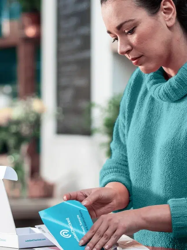 A model opens a pamphlet from her LetsGetChecked at-home fertility testing package