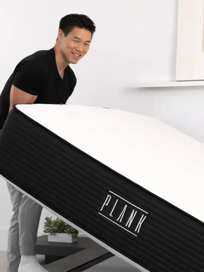 A man lifts a Plank mattress