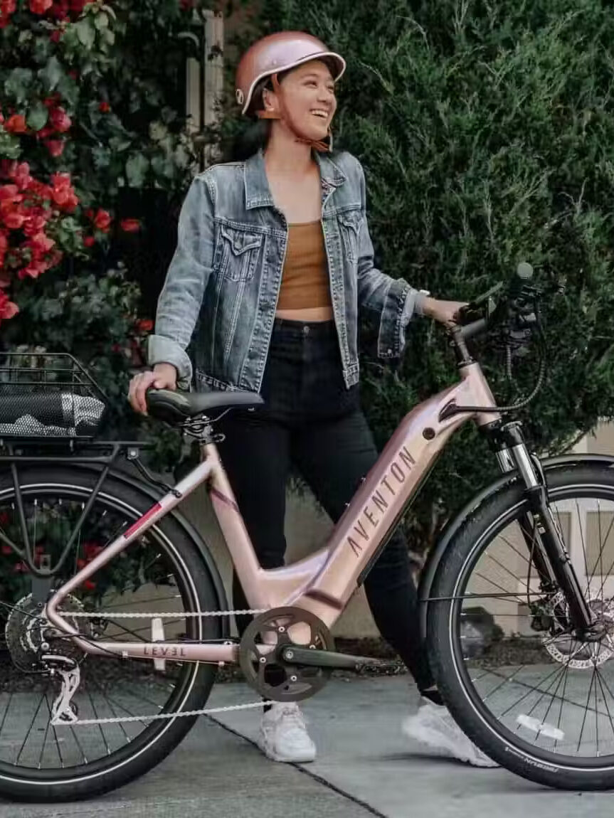A model standing next to a Aventon pink E-bike.