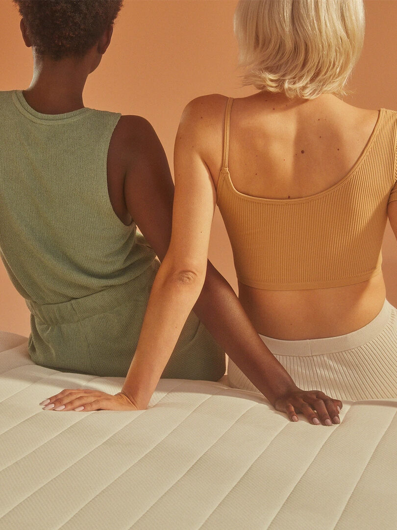 Two models sitting on an Earthfoam mattress