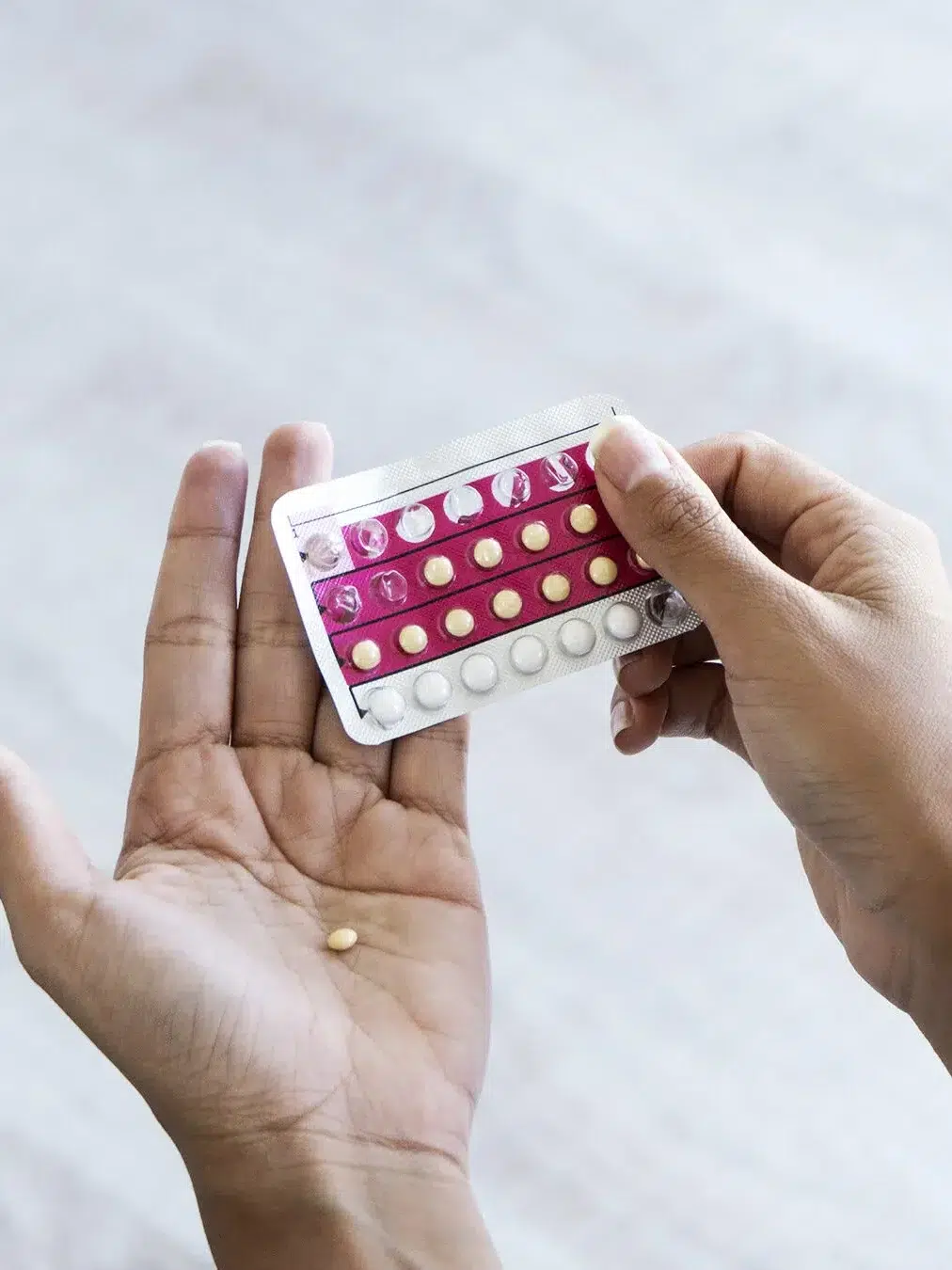 A hand opens a blister pack of birth control pills from GoodRx Care