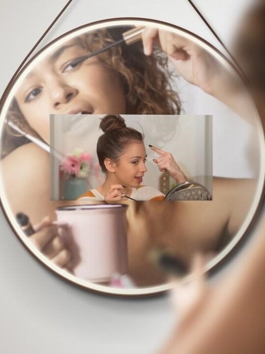 A model puts on mascara in her Hilo smart mirror while a YouTube mackeup tutorial plays.