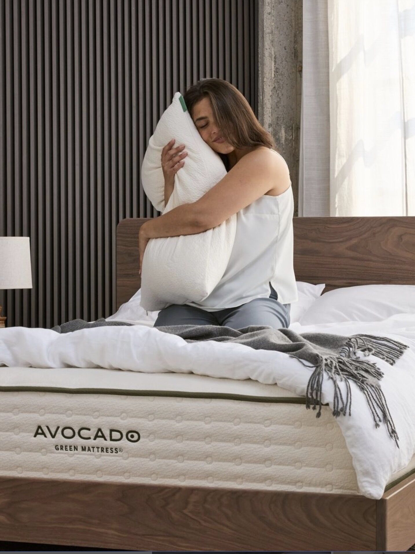 A model hugs a pillow on top of an Avocado Green Mattress