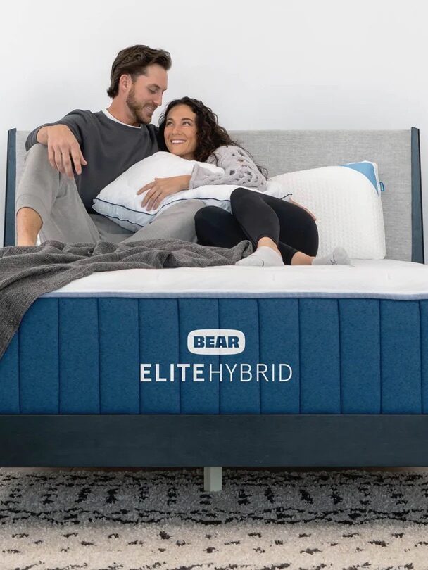 A couple snuggles on top of a Bear Elite Hybrid Mattress