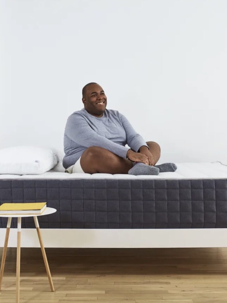 A model sits on a Helix Plus Mattress