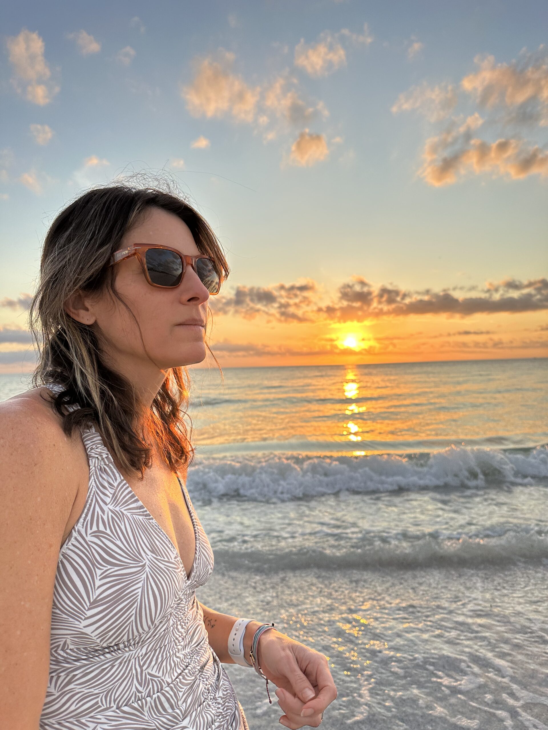 A woman standing on the beach at sunset.