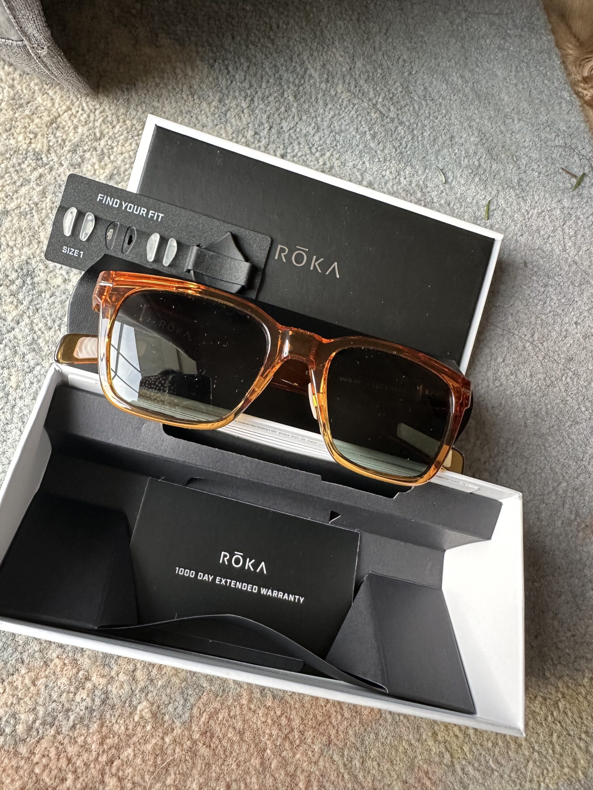 A pair of sunglasses in a box on the floor.