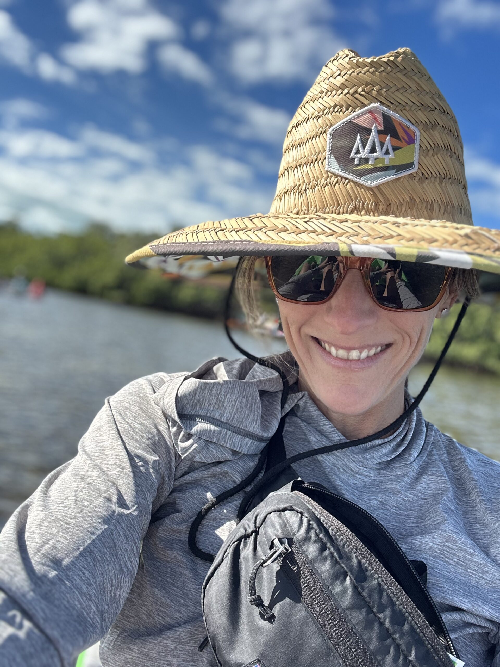 A woman wearing a straw hat and sunglasses on the water.