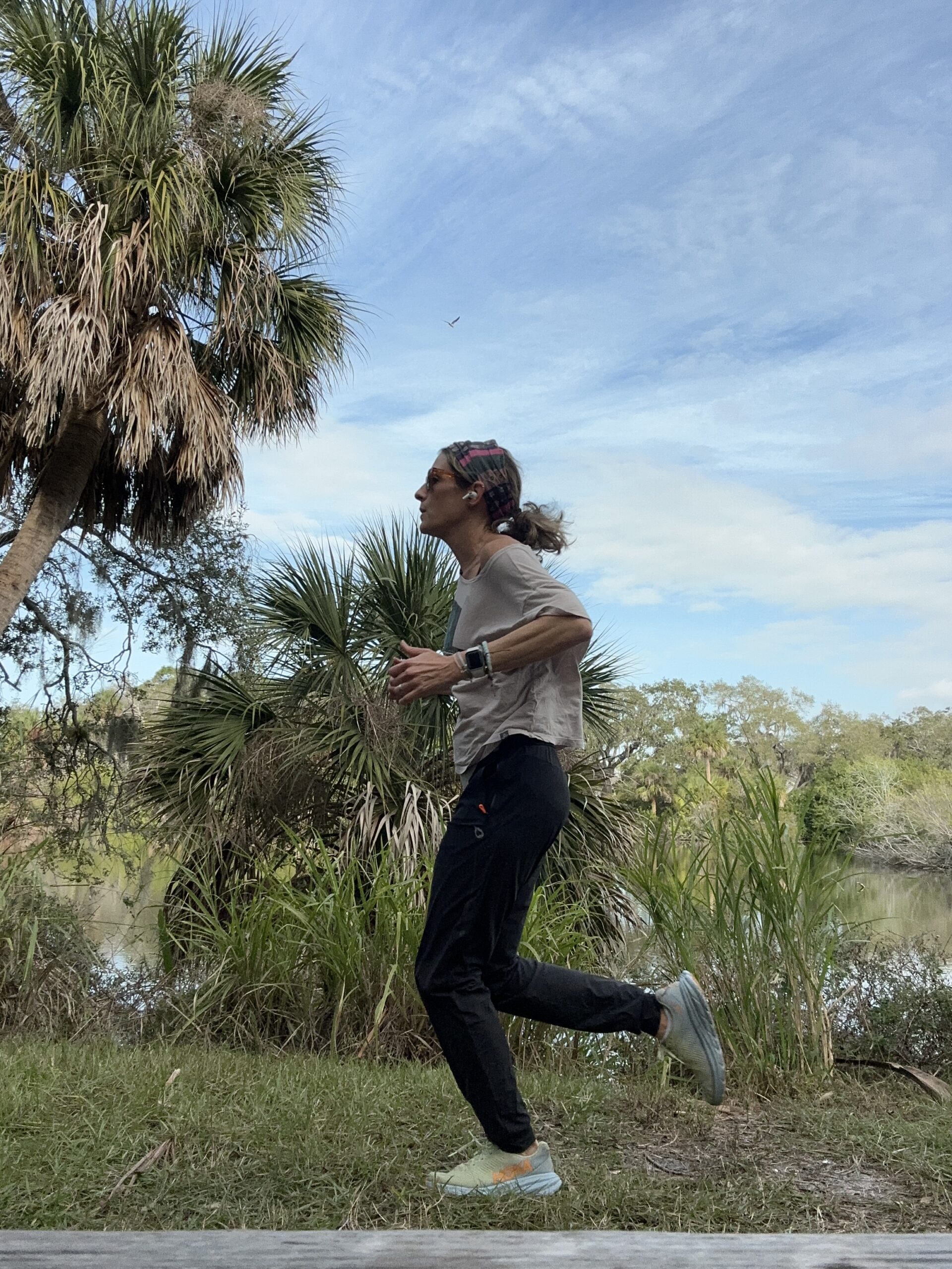A woman jogging in a park with palm trees.