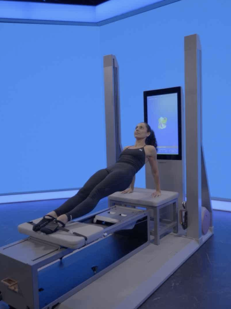 Woman exercising on a pilates reformer in a room with blue walls.