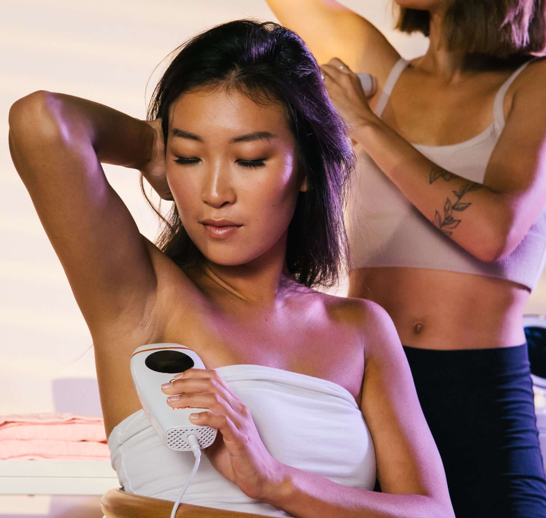 A woman is using a laser hair removal device to get rid of her armpit hair.
