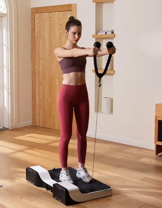 Woman exercising on a vibration plate machine with resistance bands.