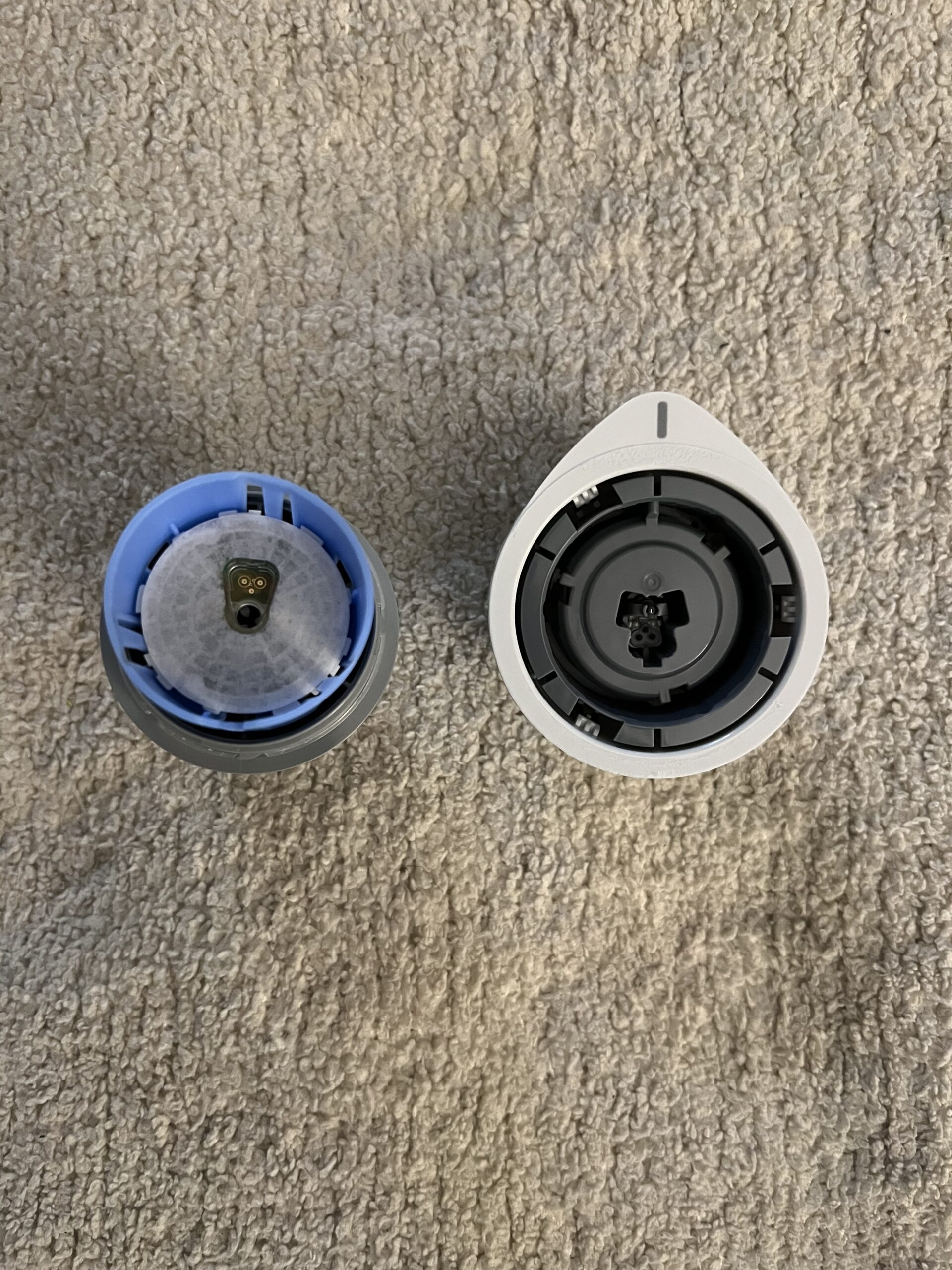 Two open water filter cartridges placed on a carpet, displaying their top internal components.