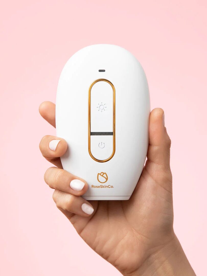 A woman's hand holding a laser hair removal device from Lumi.