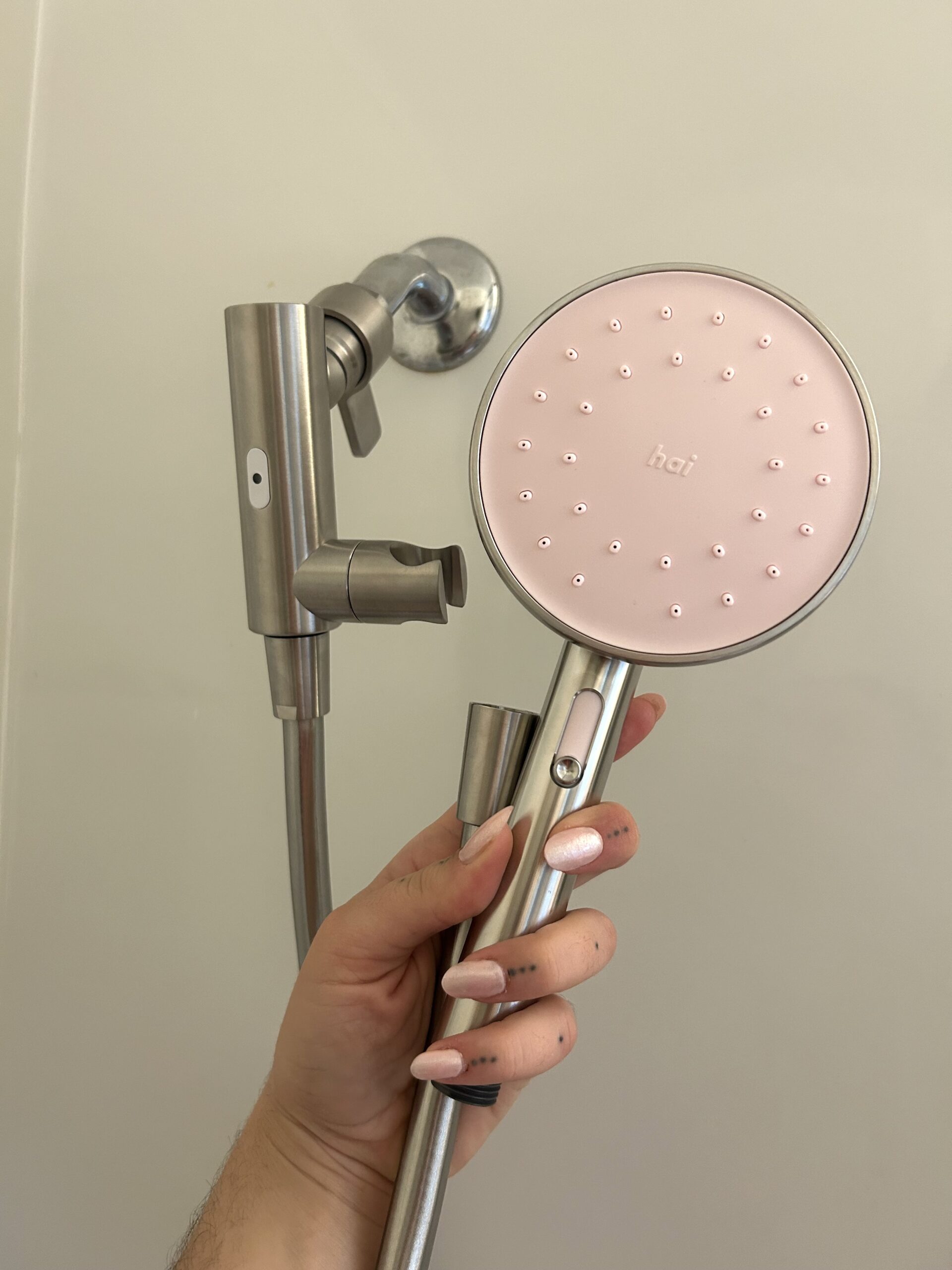 A person holding up a pink shower head.