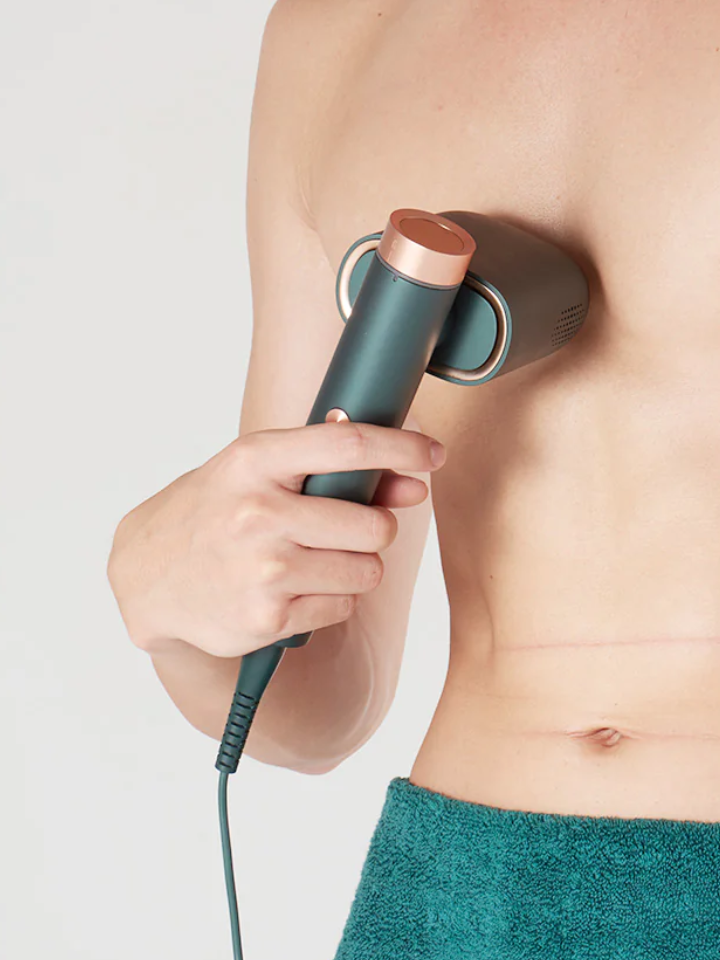 A man is holding a JOVS laser hair removal device to his chest.