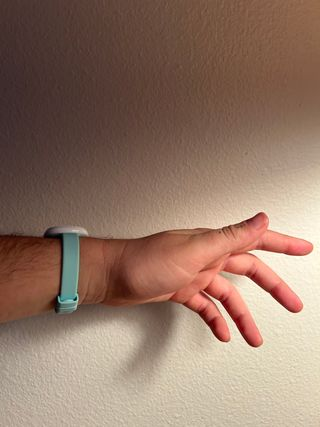 A person's wrist and hand against a plain background, wearing a light blue wristband.