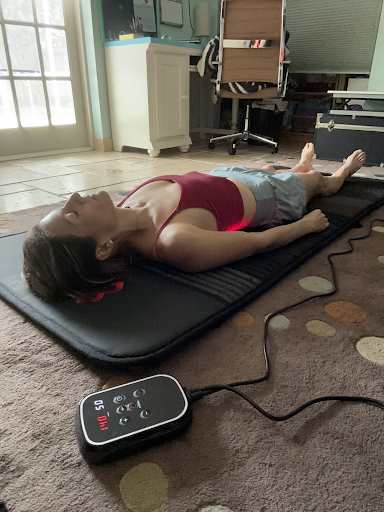 A person lying on a back massage mat with a remote control nearby, relaxing indoors.