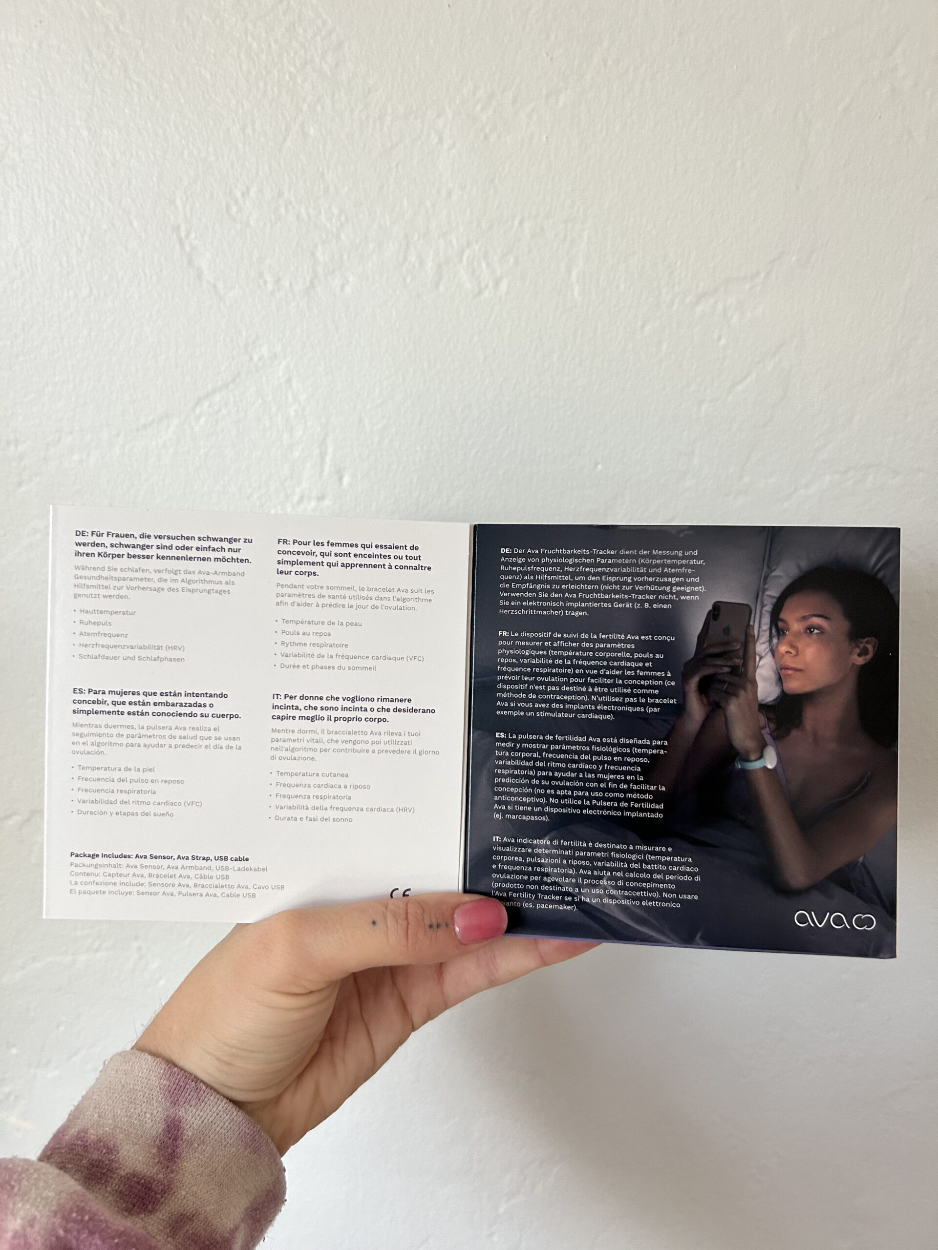 A person holds a brochure with text and an image of a woman using a smartphone.