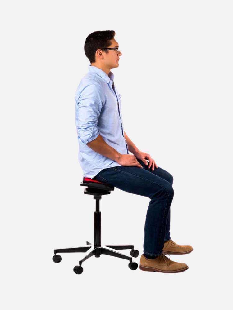 Young man wearing glasses, a blue shirt, and jeans sitting on a black office chair in profile view, isolated on a white background.