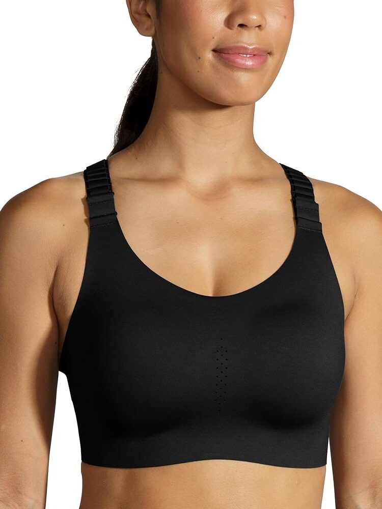 A person wearing a black sports bra with adjustable straps holds one of the latest massage guns, perfectly blending fitness and recovery in style.