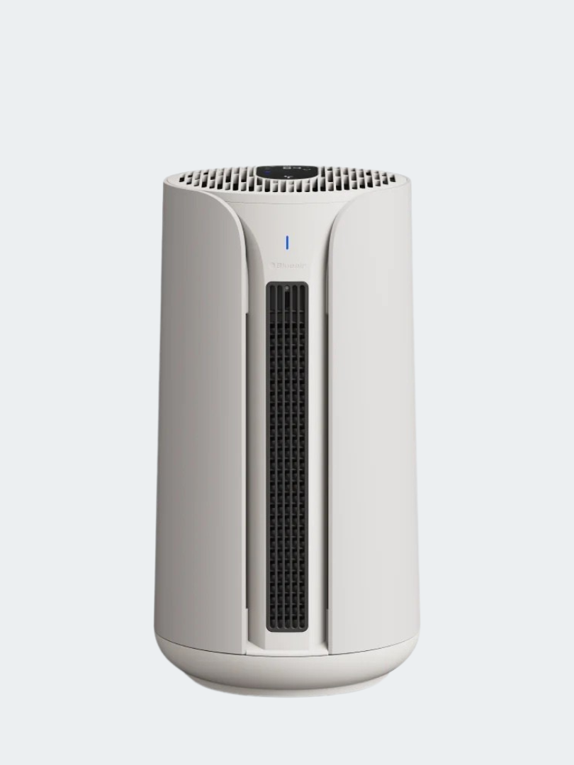 A white, cylindrical air purifier with a vertical black vent and small indicator light on the front, set against a plain light background—an essential companion for spaces that also feature wellness devices like massage guns.