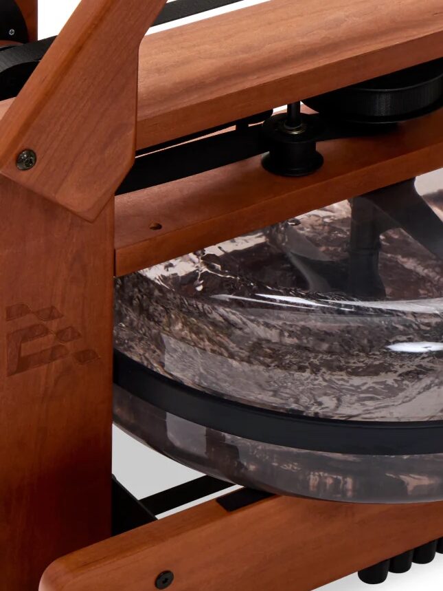 Close-up of a wooden rowing machine featuring a transparent water tank with swirling water inside, ideal for pairing with massage guns for enhanced muscle recovery after your workout.