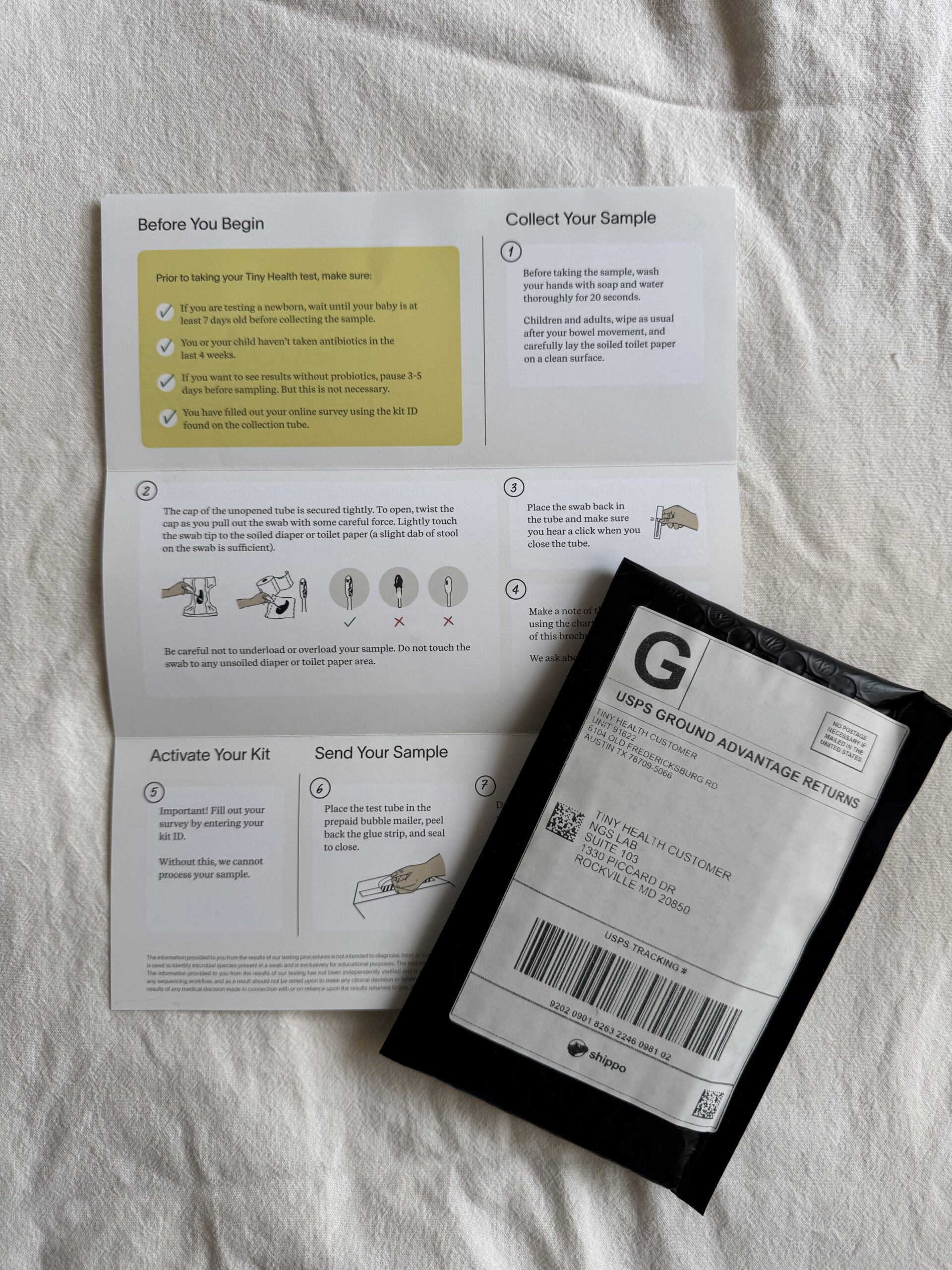 Instruction pamphlet for a health test kit is laid out next to a black, pre-labeled USPS return mailer on a white surface.