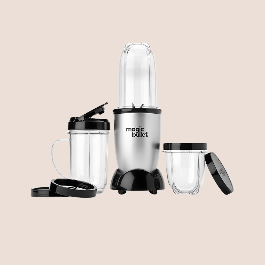 A Magic Bullet blender with a main base, blending cup, two additional cups with lids, and two extra rings is displayed on a light beige background—perfect for those who love wellness gadgets like massage guns.