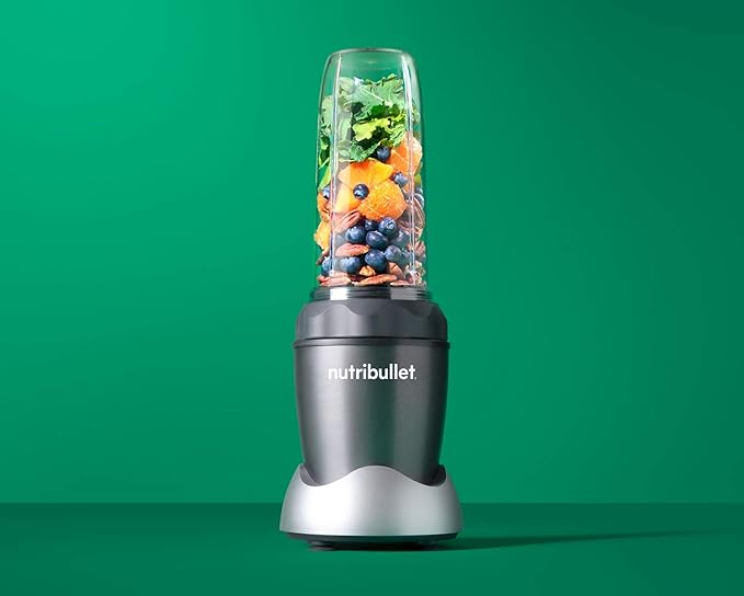 A Nutribullet blender filled with assorted fruits, leafy greens, and nuts sits against a green background—perfect fuel for post-workout recovery alongside massage guns.
