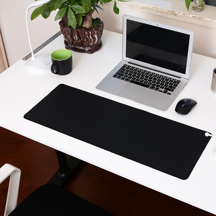 A white desk with a laptop, black mouse, green mug, desk lamp, potted plant, a large black mouse pad, and space for accessories like massage guns.