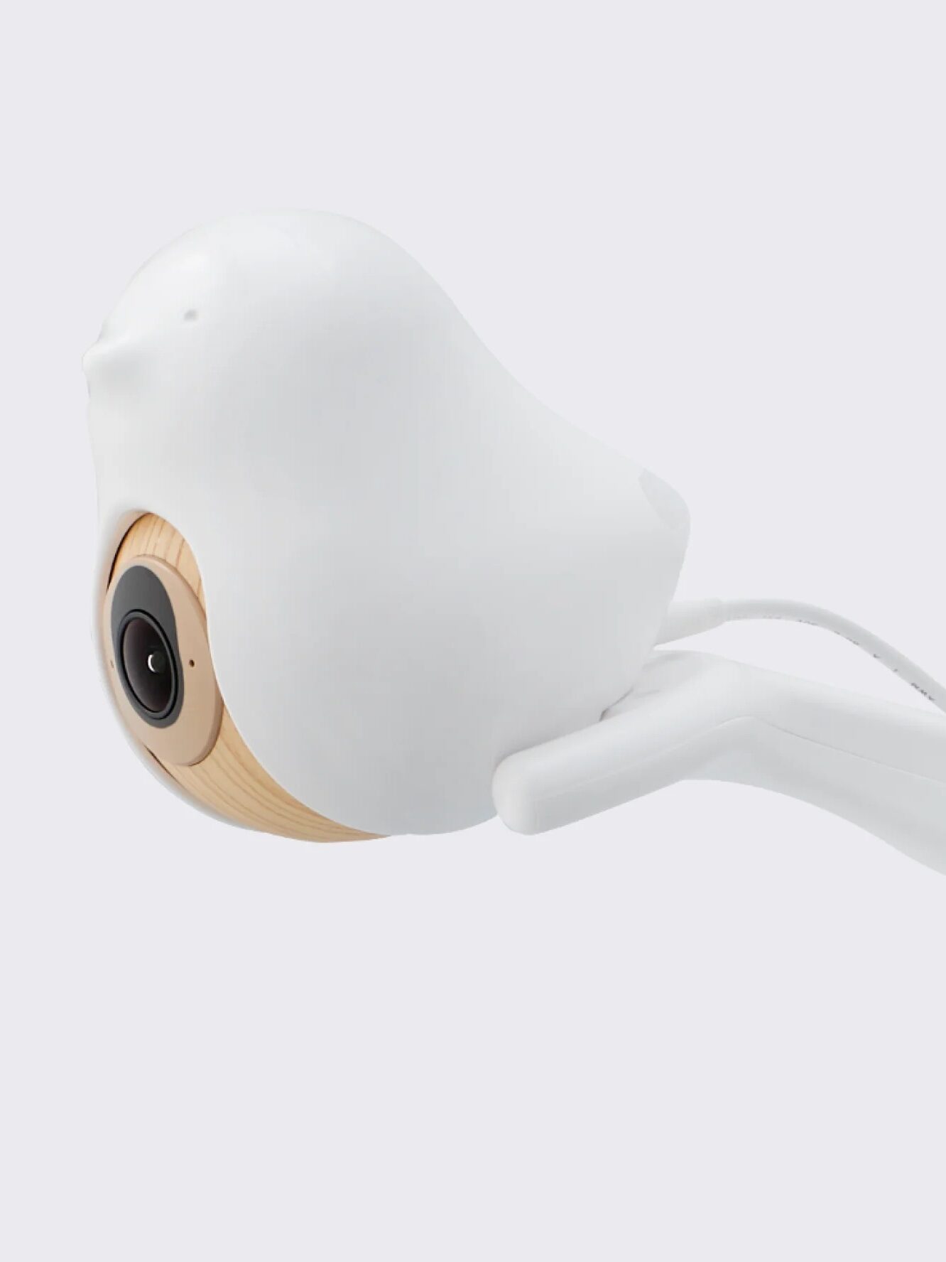 A white bird-shaped baby monitor camera is shown next to a smartphone displaying a baby monitoring app interface, ideal for parents who appreciate modern nursery tech like massage guns and smart gadgets.