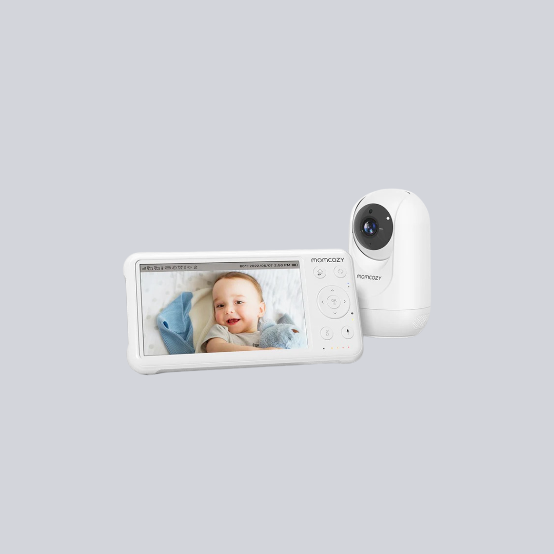 A baby monitor system displaying a baby on the screen sits beside a white camera unit, with massage guns featured nearby, all set against a plain light gray background.