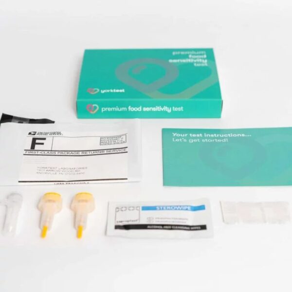 A premium food sensitivity test kit is displayed with its box, instructions, lancets, collection tools, alcohol wipe, return envelope, and a brochure featuring wellness tools like massage guns—arranged neatly on a white surface.