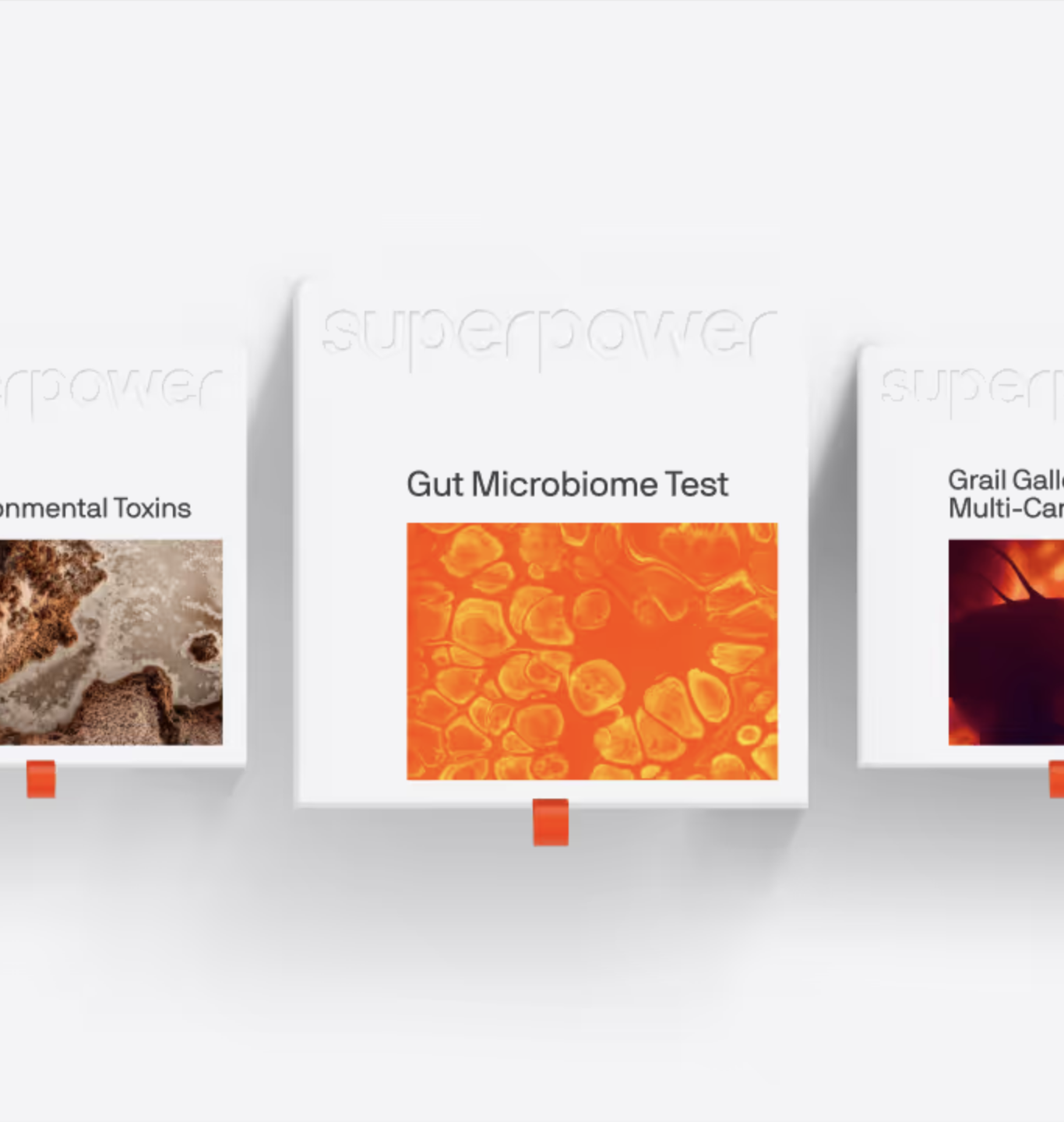 Three white boxes on a white background labeled "Environmental Toxins," "Gut Microbiome Test," and "Grail Galleri Multi-Cancer," each with an abstract image, an orange pull tab, and massage guns displayed alongside for a wellness-focused touch.