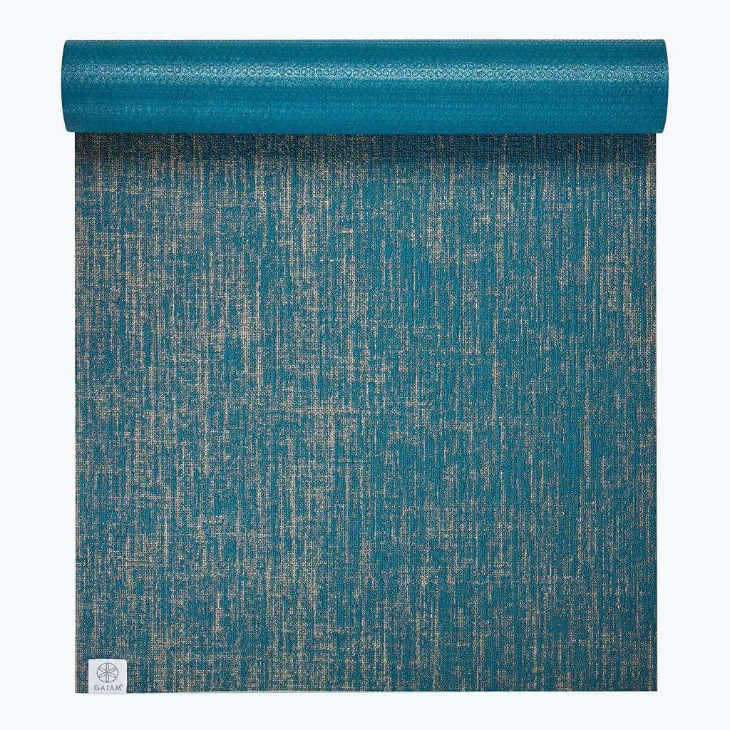 A rolled-out blue textured yoga mat with a subtle mottled pattern and a small logo in the bottom corner.