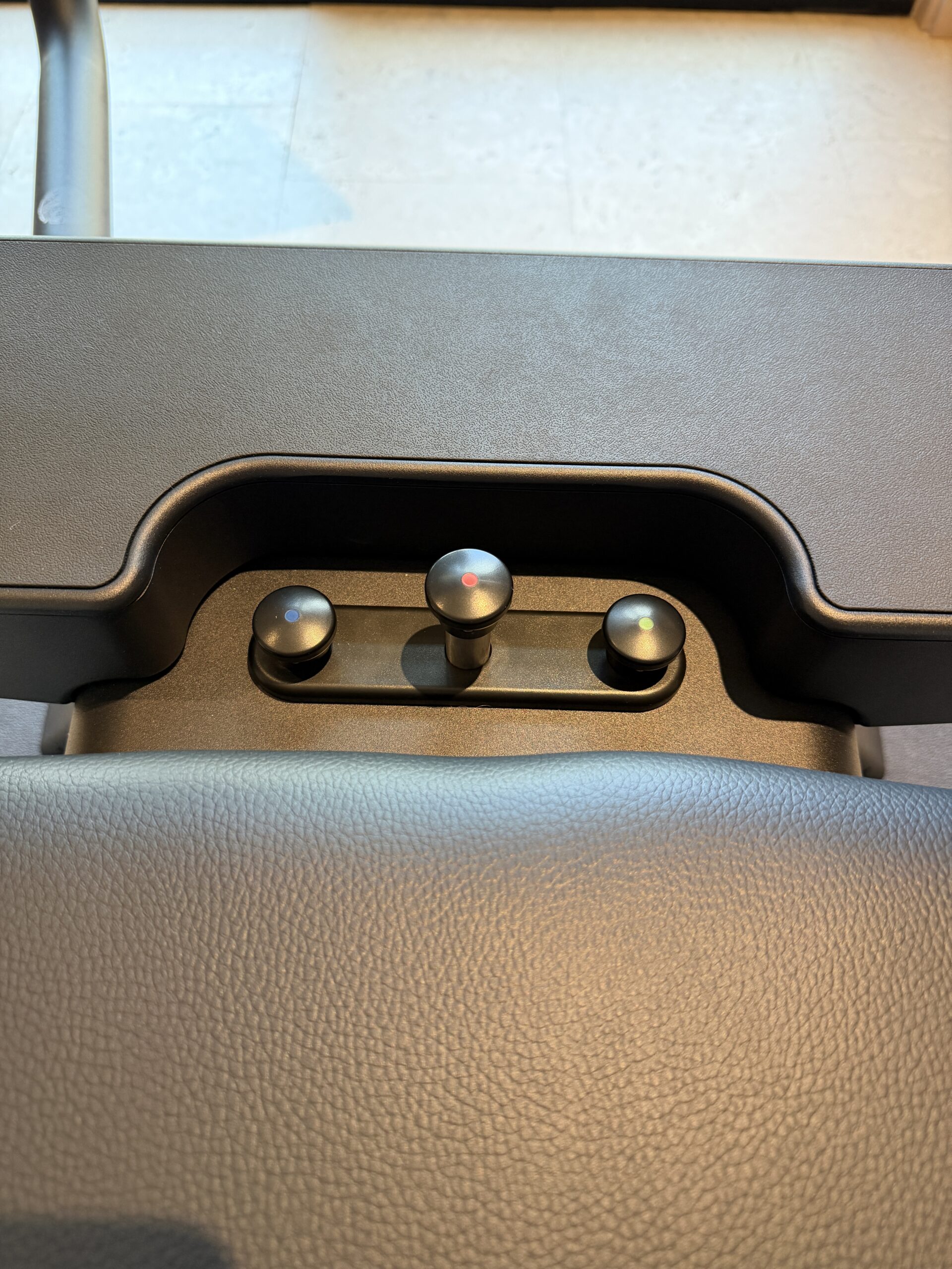 Three round control knobs set into a console, marked with blue, red, and green dots.